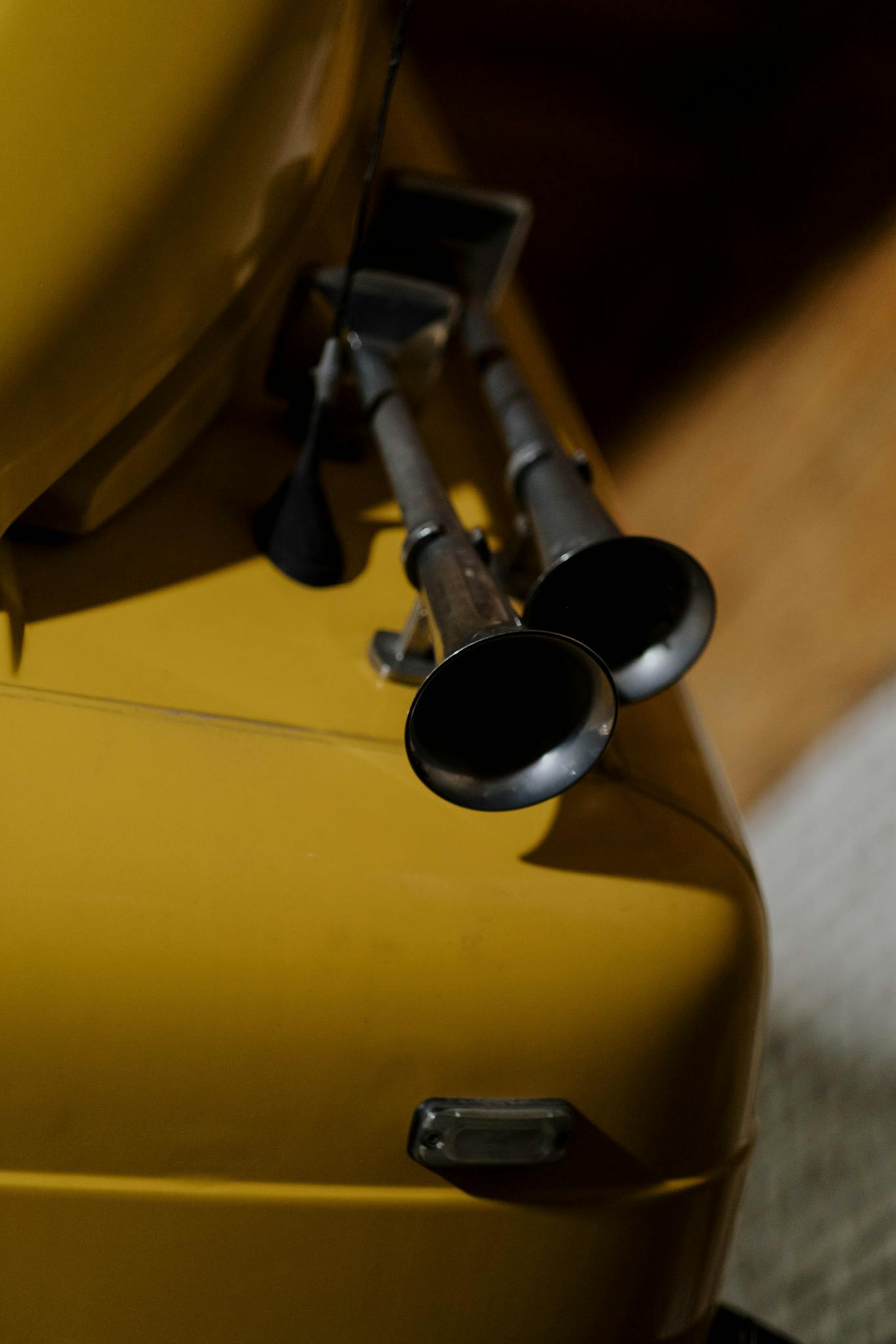 Detailed view of air horns on a yellow vintage car exterior part.