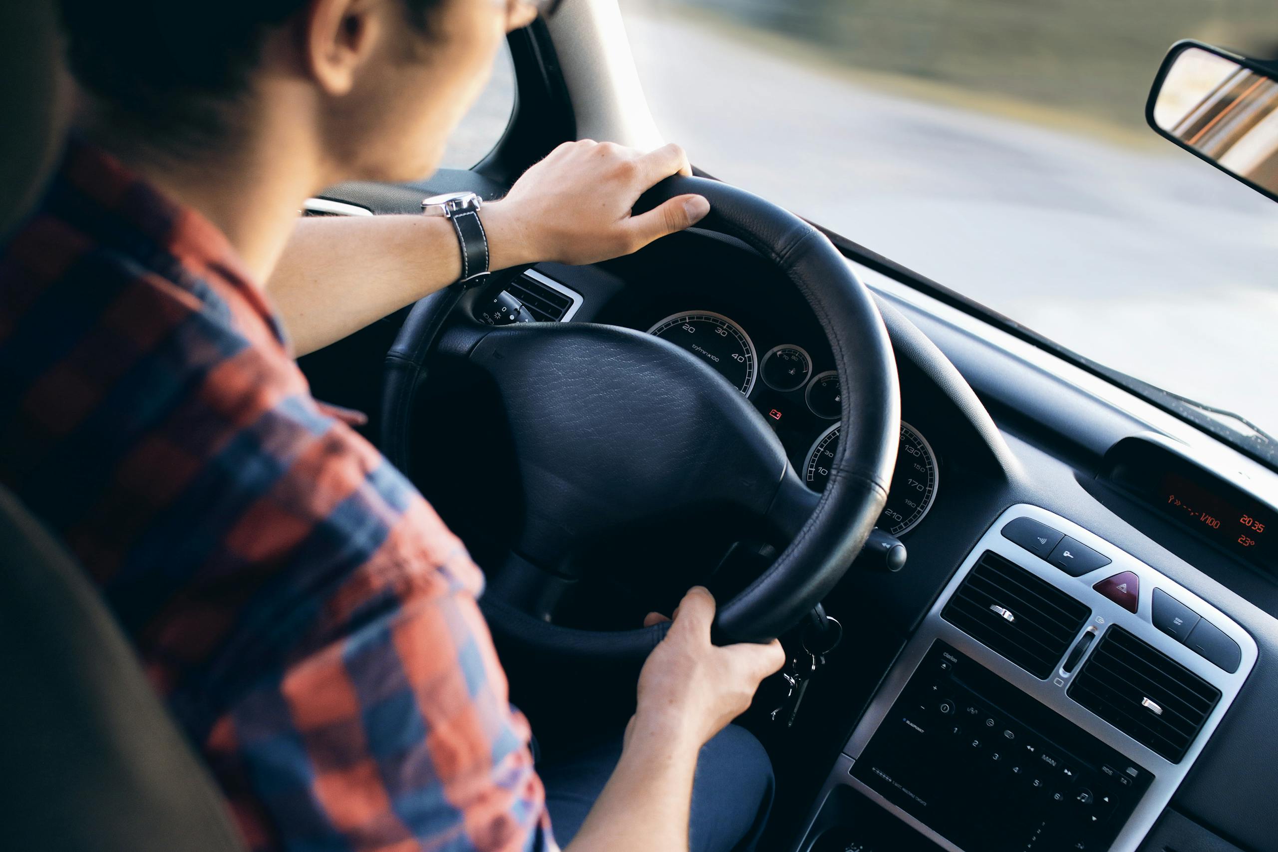 Close-up view of a man driving a modern car, showing dashboard and steering details.